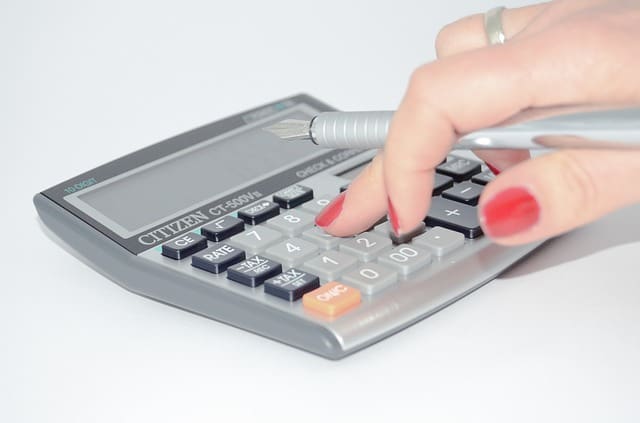 Lady pressing small calculator with pen in her hand.