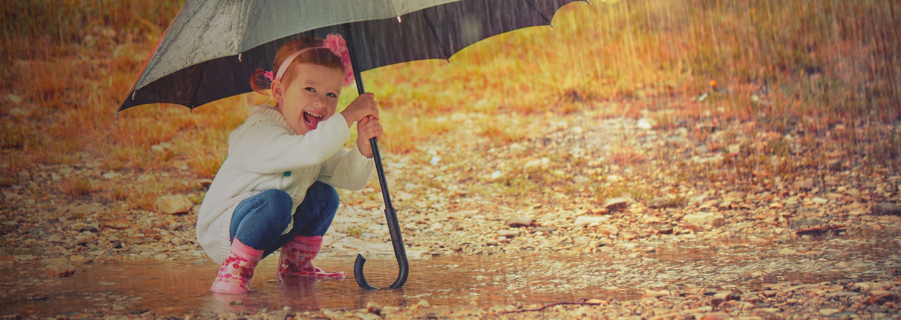 young girl playing in rain with umbrella