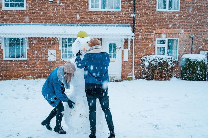Choosing the right location | A couple making a snowman outside of their new home