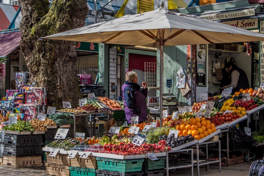 Living in Norwich | Image of a fruit and veg market and someone buying wares