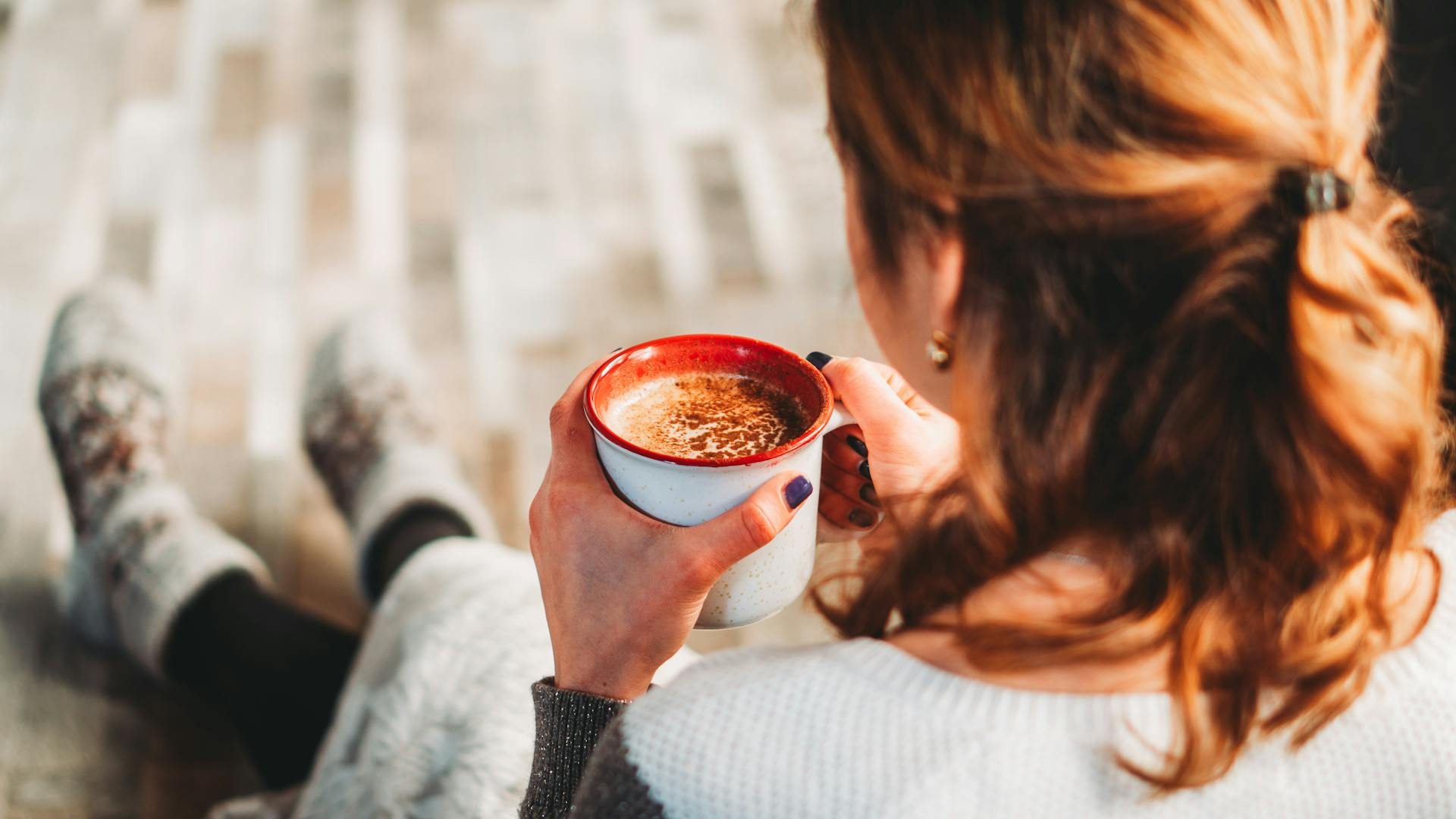 A woman enjoying a coffee in her home in comfy socks after looking into bad credit bridging loans