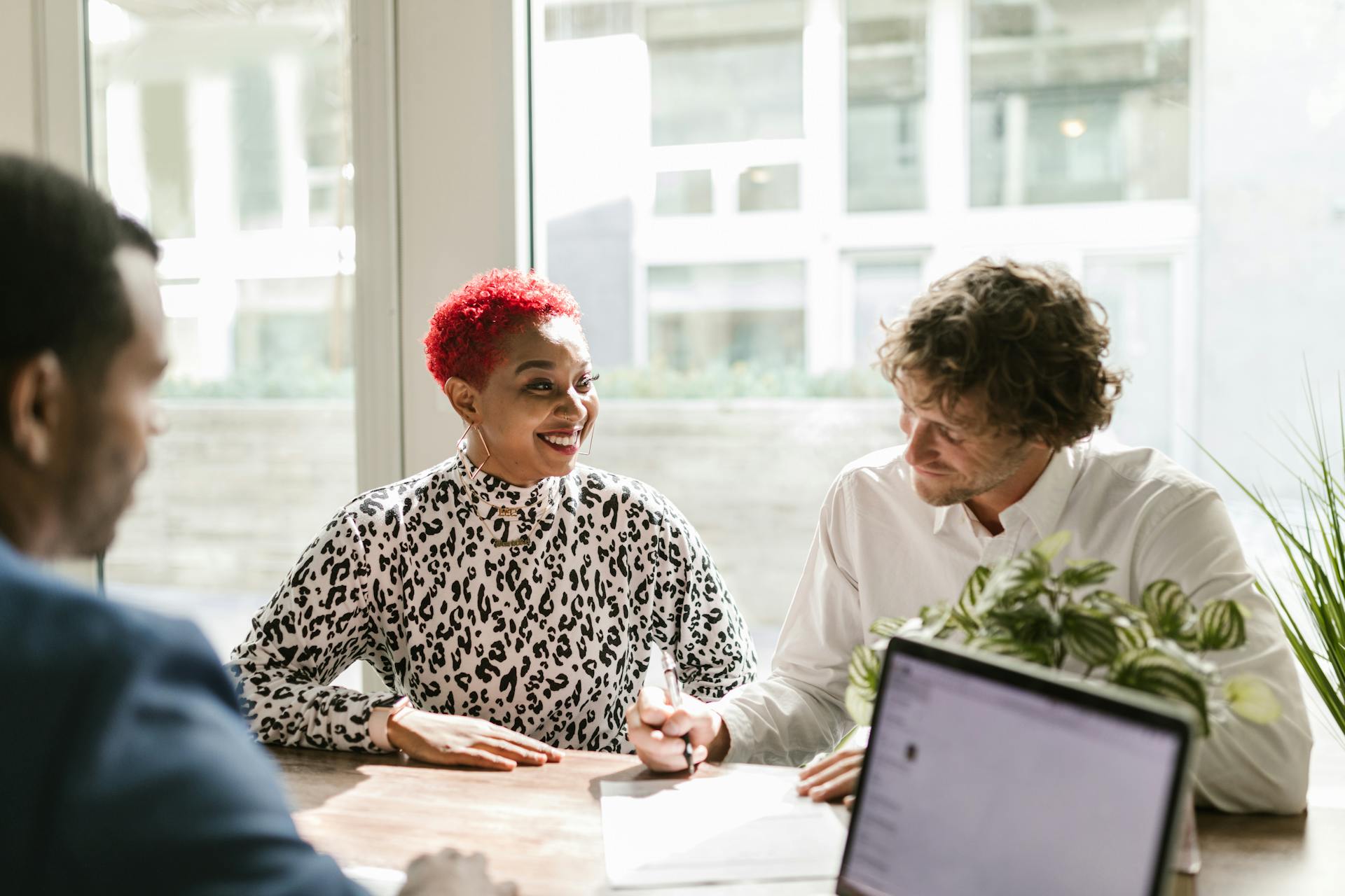 A couple sitting round a desk with a financial advisor seeking options for secured loans for debt consolidation